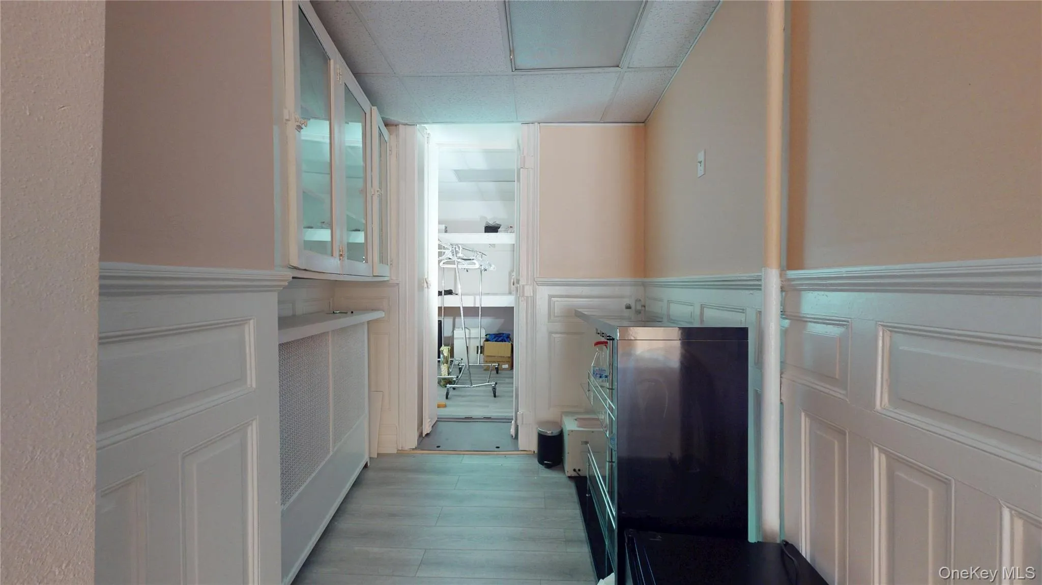 Corridor featuring dark wood-style floors, a wainscoted wall, and a decorative wall Corridor featuring dark wood-style floors, a wainscoted wall, and a decorative wall