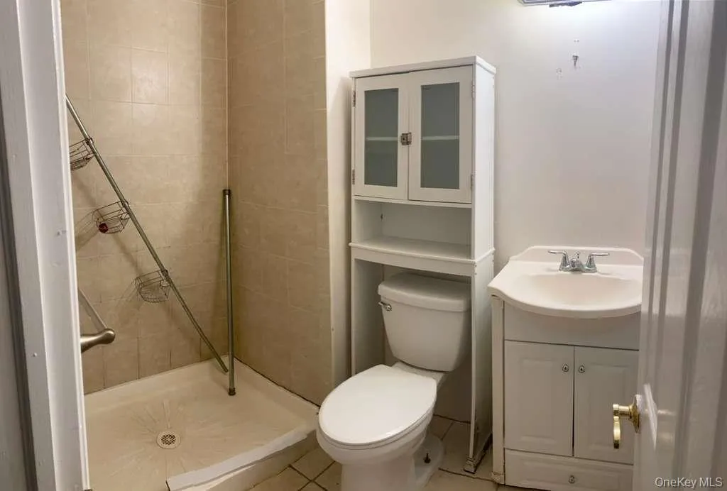 Full bathroom with a stall shower, vanity, and light tile patterned floors Full bathroom with a stall shower, vanity, and light tile patterned floors