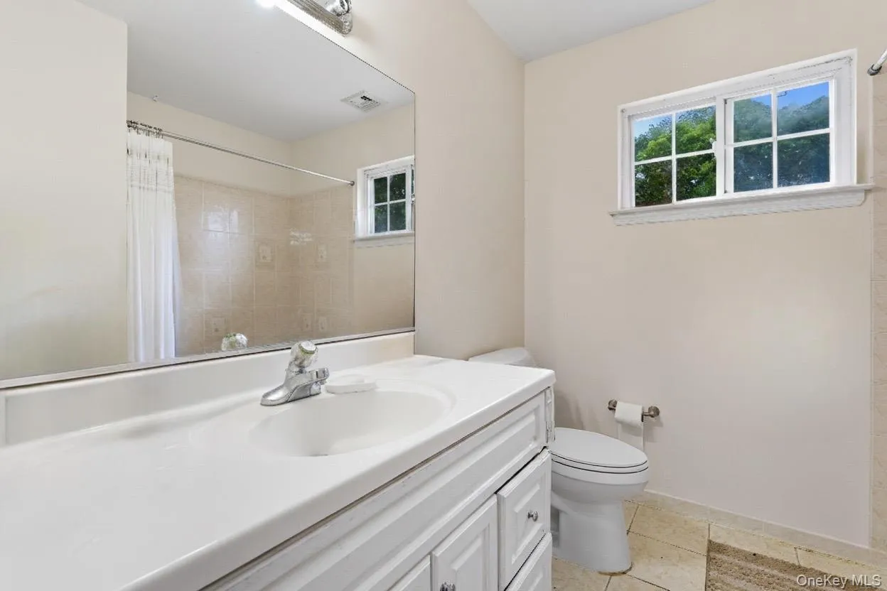 Full bath featuring vanity, light tile patterned floors, and a shower with shower curtain Full bath featuring vanity, light tile patterned floors, and a shower with shower curtain