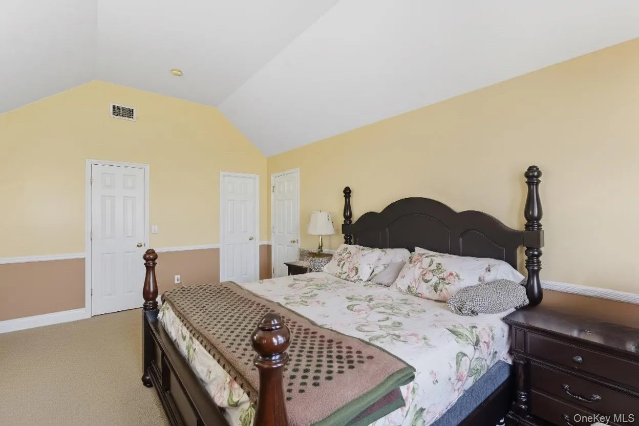 Carpeted bedroom featuring vaulted ceiling Carpeted bedroom featuring vaulted ceiling