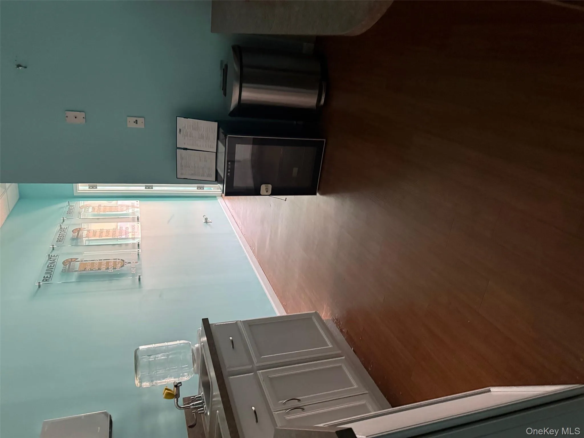 Kitchen with dark wood-style flooring, white cabinets, and dark countertops Kitchen with dark wood-style flooring, white cabinets, and dark countertops