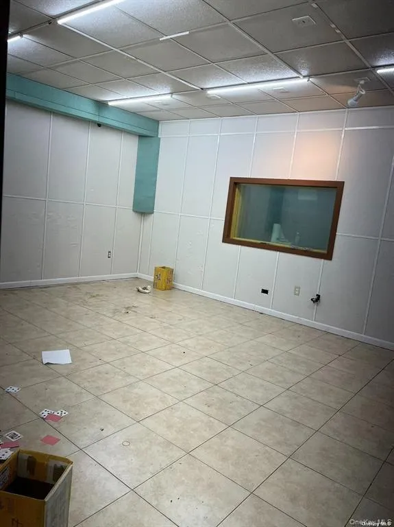 Basement with a drop ceiling and light tile patterned floors Basement with a drop ceiling and light tile patterned floors