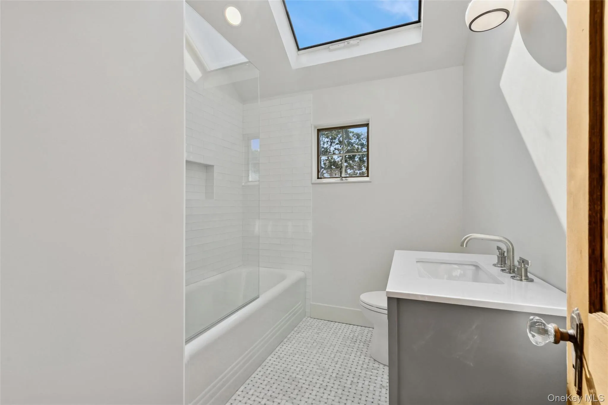 Bathroom featuring vanity, bathing tub / shower combination, tile patterned flooring, and a skylight Bathroom featuring vanity, bathing tub / shower combination, tile patterned flooring, and a skylight