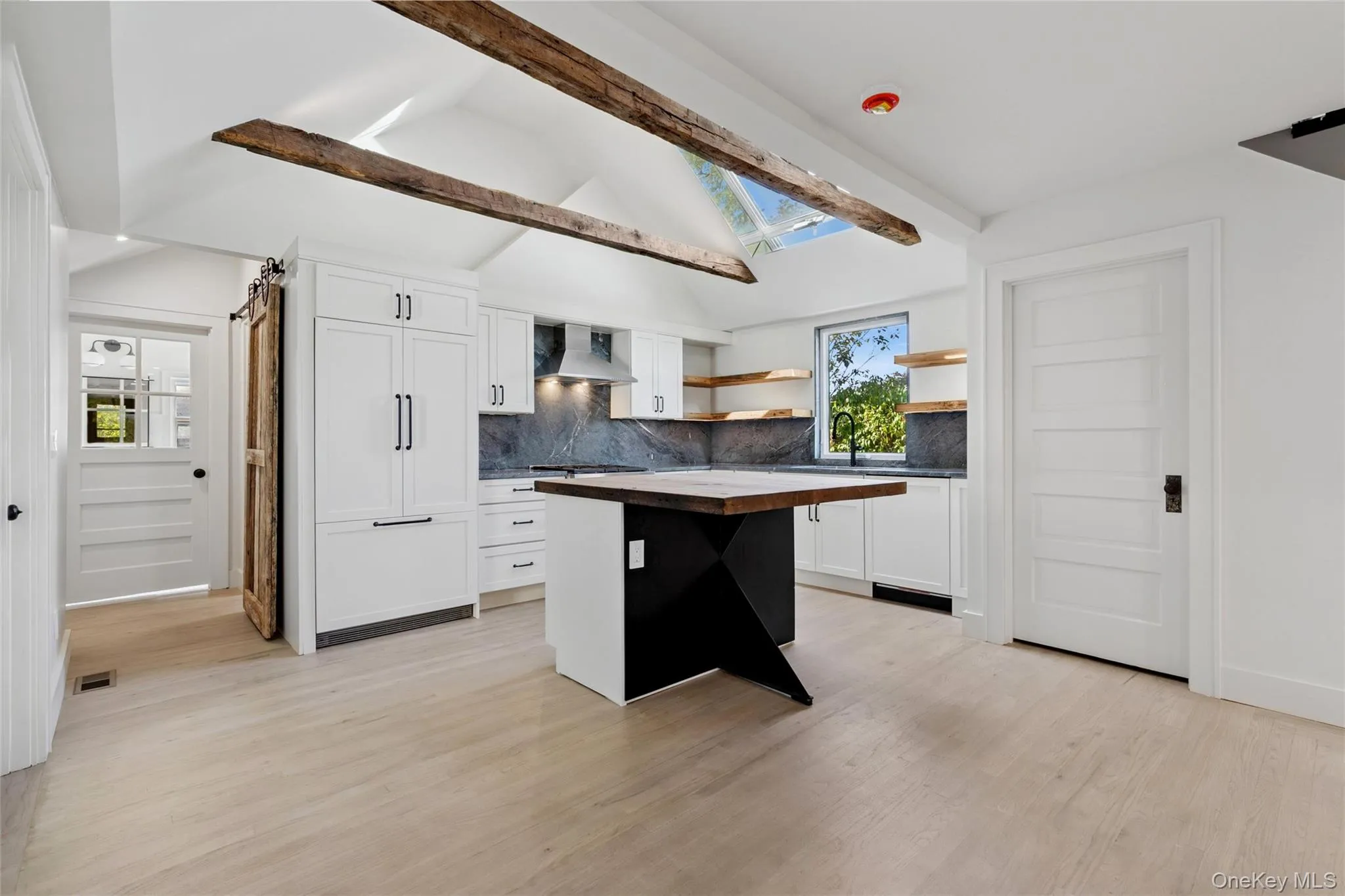 Kitchen with white cabinets, open shelves, tasteful backsplash, a kitchen island, and light wood-style flooring Kitchen with white cabinets, open shelves, tasteful backsplash, a kitchen island, and light wood-style flooring