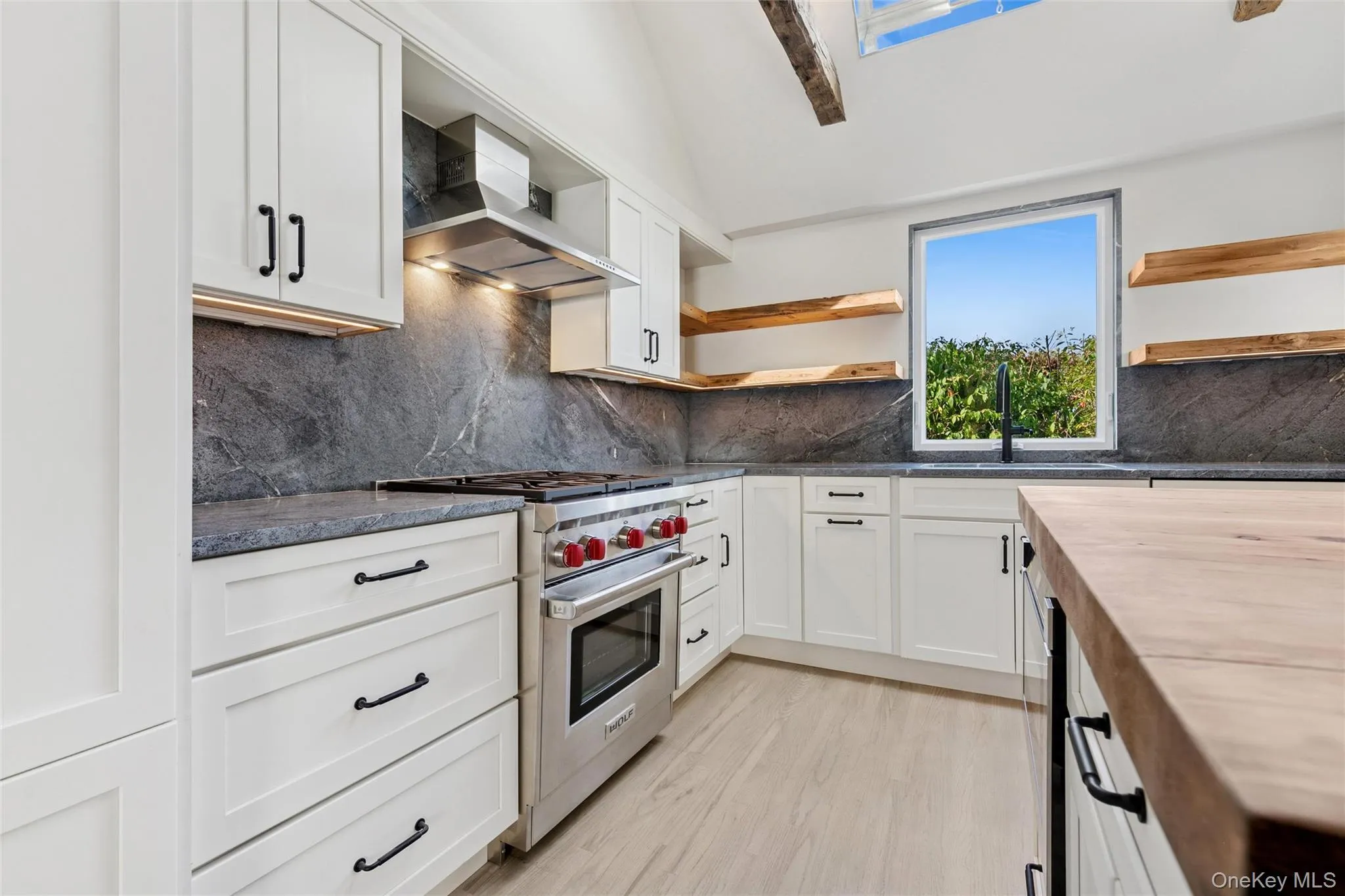 Kitchen with wooden counters, white cabinetry, luxury stove, and open shelves Kitchen with wooden counters, white cabinetry, luxury stove, and open shelves