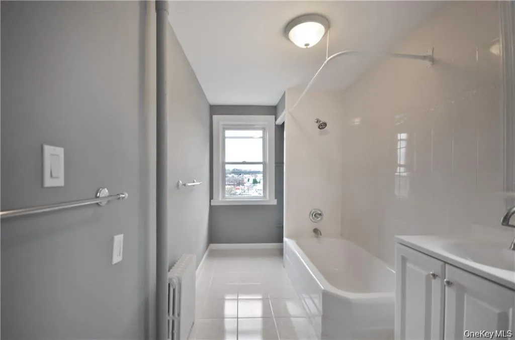 Bathroom featuring  shower combination, vanity, radiator, and light tile patterned flooring Bathroom featuring  shower combination, vanity, radiator, and light tile patterned flooring