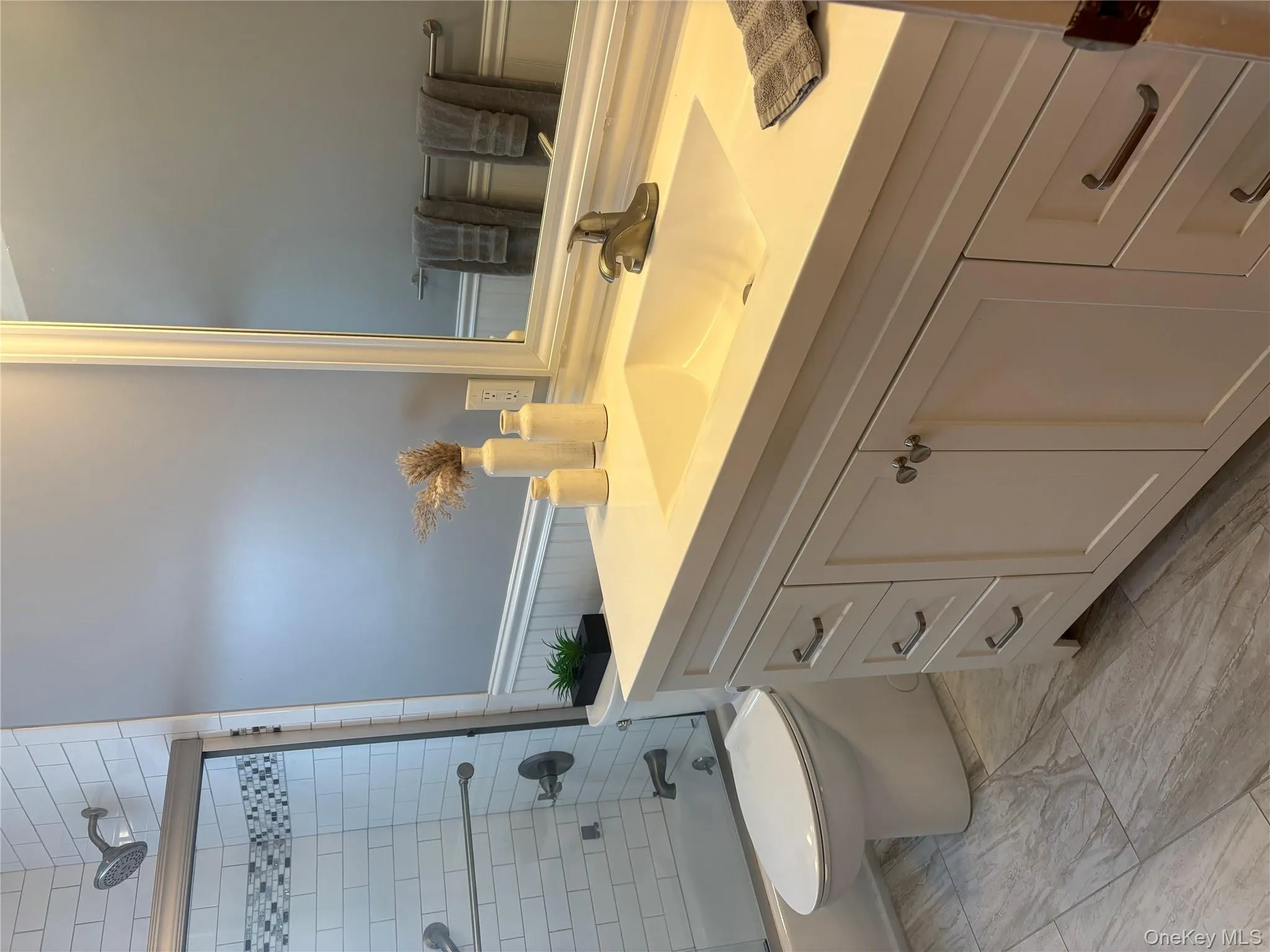 Bathroom with wainscoting, vanity, and bath / shower combo with glass door Bathroom with wainscoting, vanity, and bath / shower combo with glass door