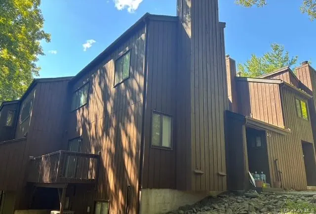 View of property exterior featuring a chimney, board and batten siding, and a gambrel roof View of property exterior featuring a chimney, board and batten siding, and a gambrel roof