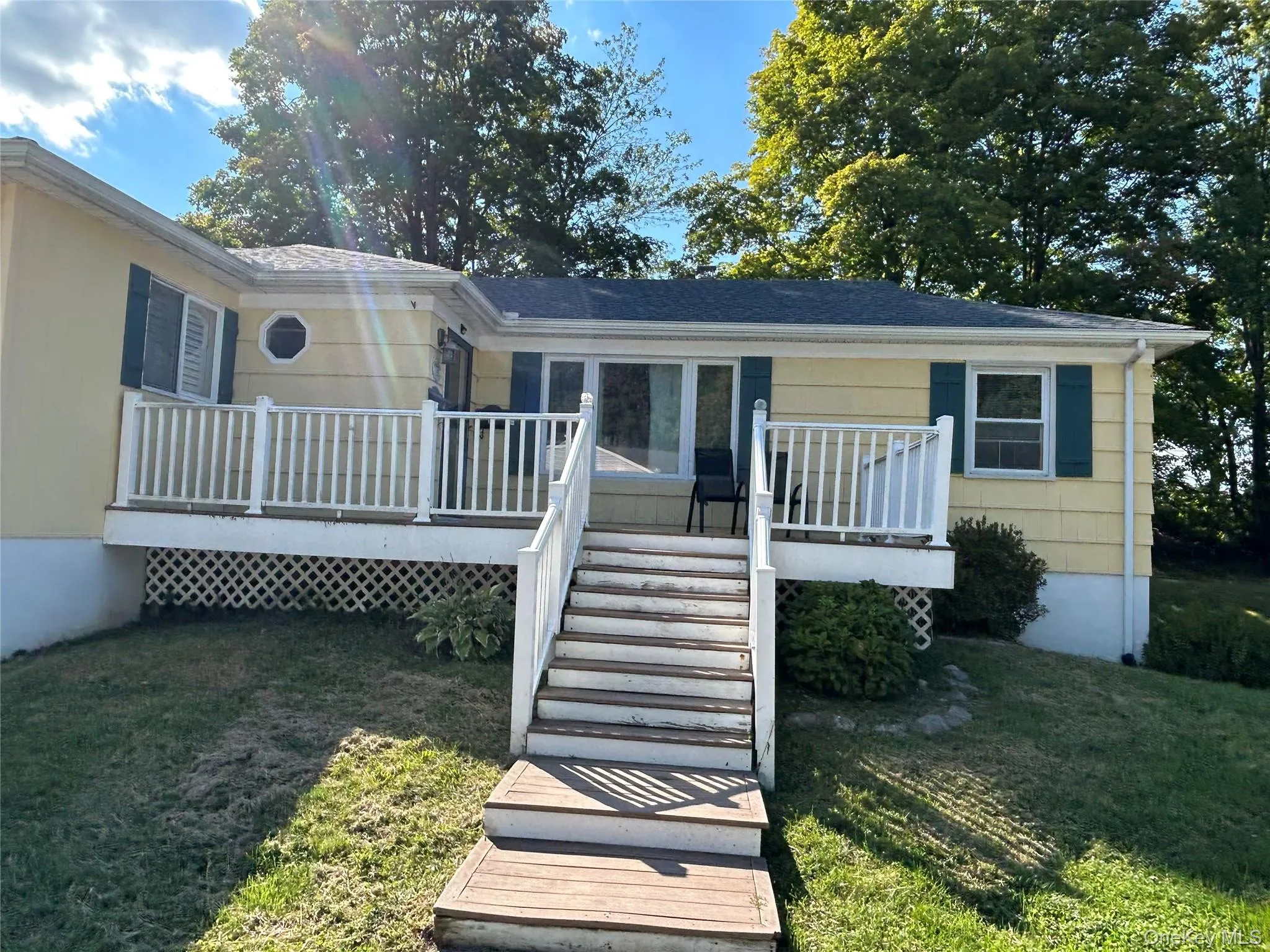 Front entrance of property featuring a lawn, a front deck, and stairway Front entrance of property featuring a lawn, a front deck, and stairway