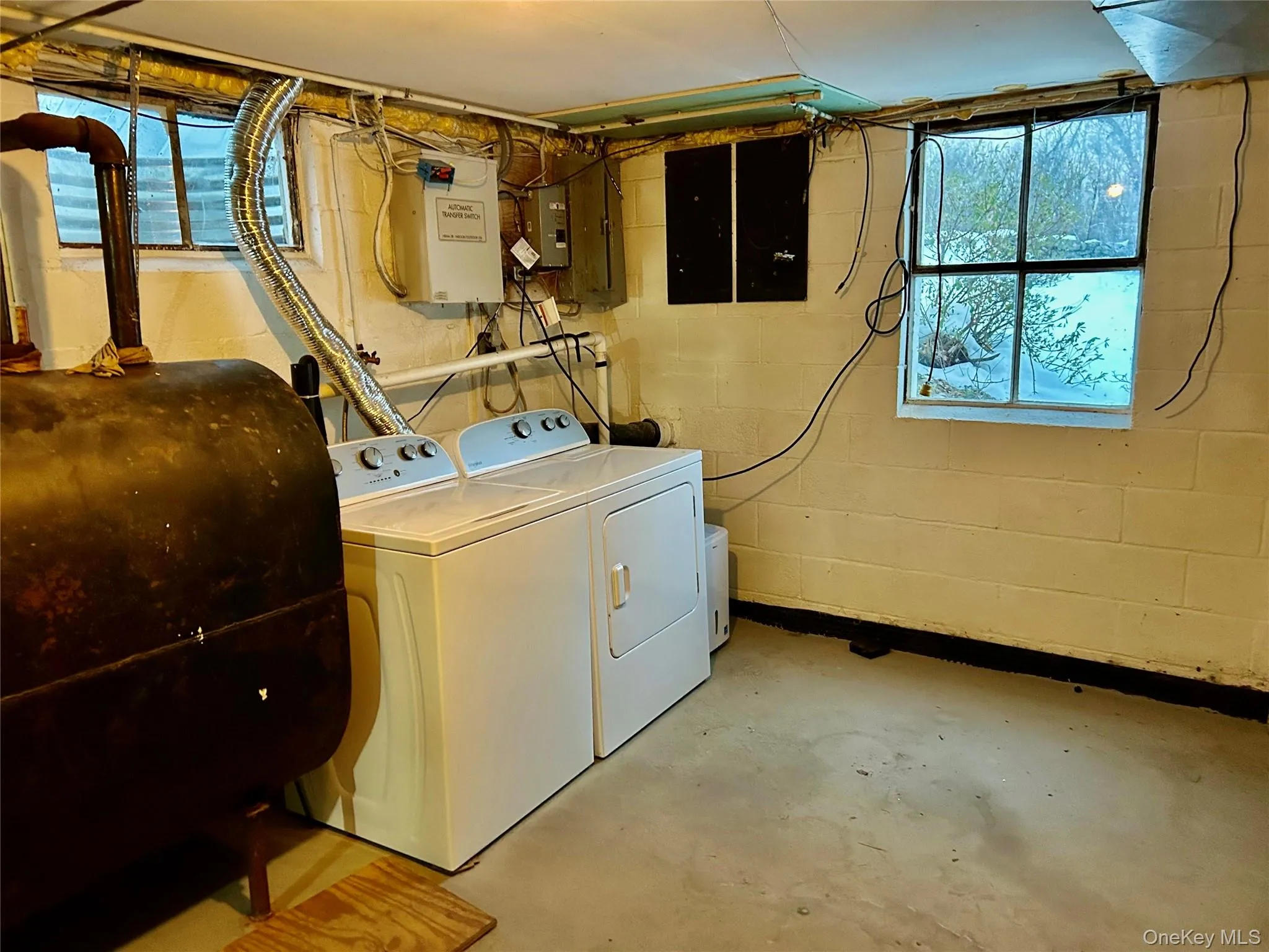 Laundry room with oil tank, concrete flooring, washer and clothes dryer, and electric panel Laundry room with oil tank, concrete flooring, washer and clothes dryer, and electric panel