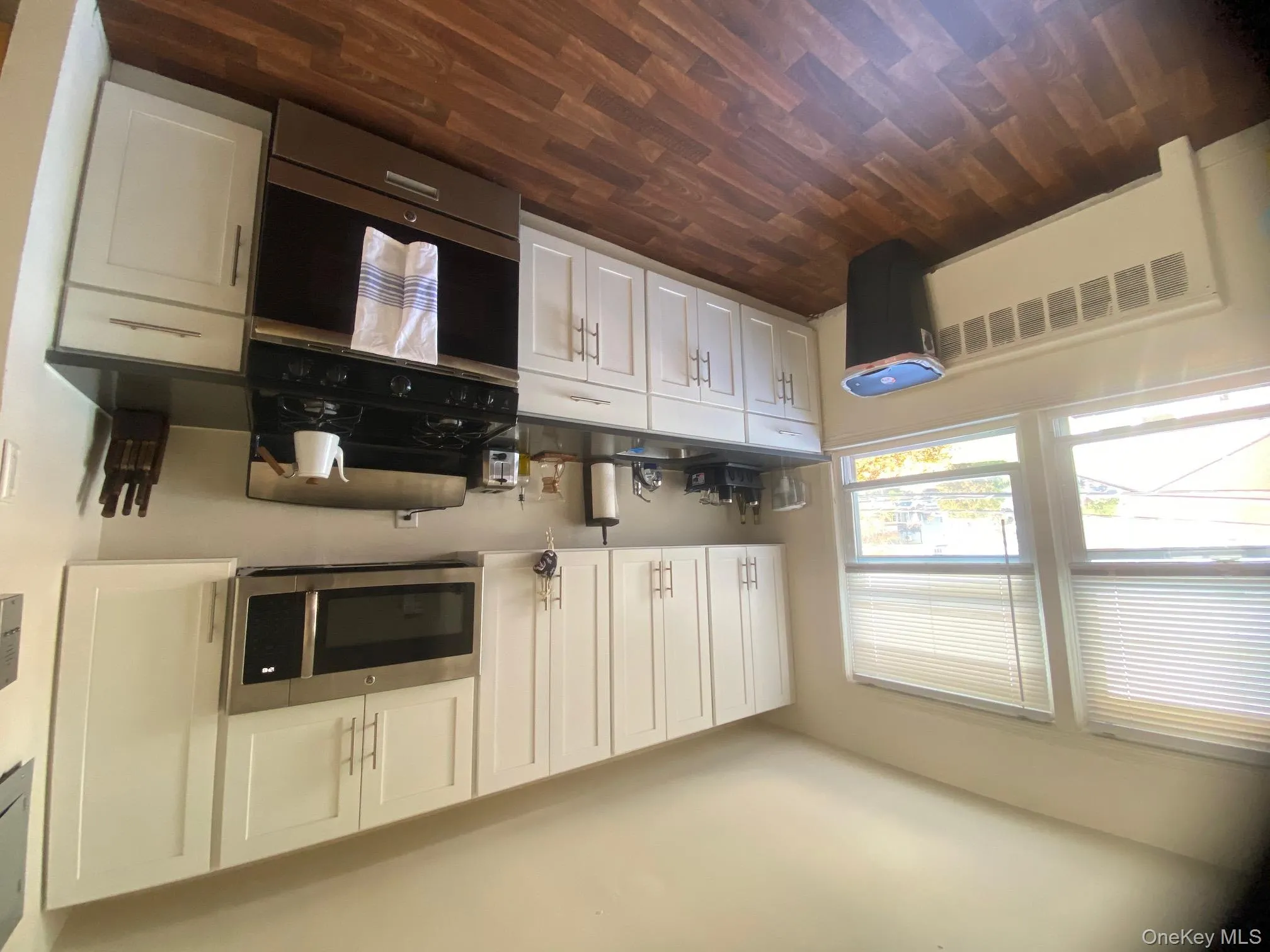 Kitchen with dark countertops, stove, white cabinets, and radiator heating unit Kitchen with dark countertops, stove, white cabinets, and radiator heating unit