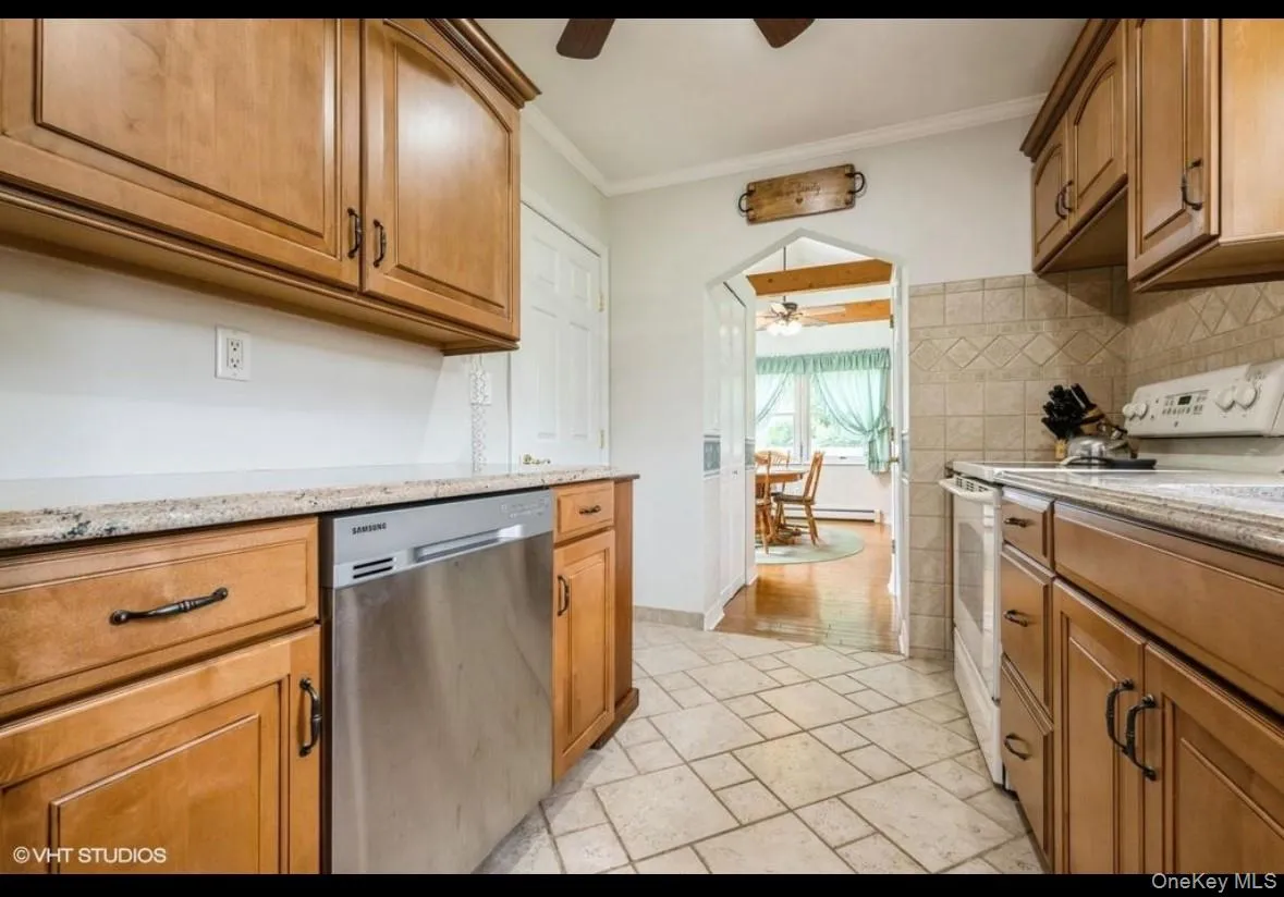Kitchen featuring ceiling fan, electric range, stainless steel dishwasher, ornamental molding, and light stone countertops Kitchen featuring ceiling fan, electric range, stainless steel dishwasher, ornamental molding, and light stone countertops