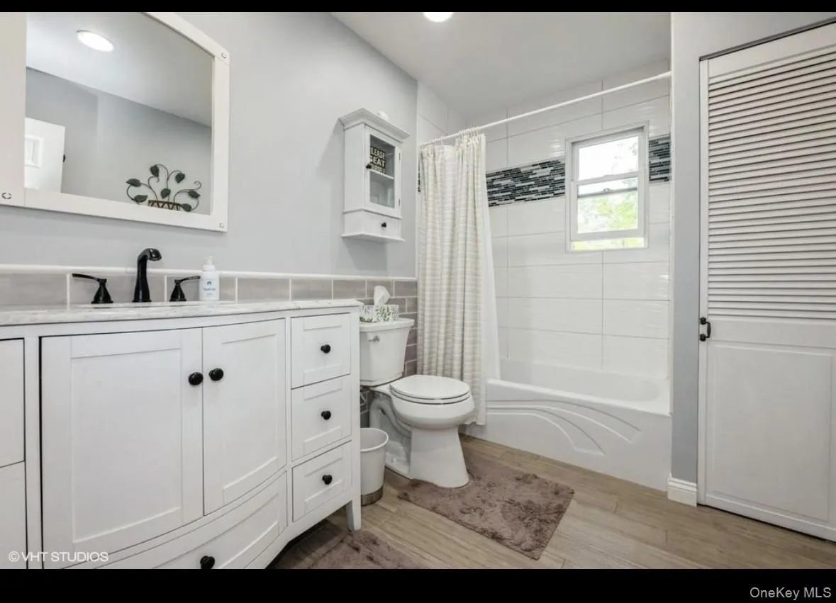 Full bathroom featuring shower / tub combo, vanity, light wood-type flooring, and recessed lighting Full bathroom featuring shower / tub combo, vanity, light wood-type flooring, and recessed lighting