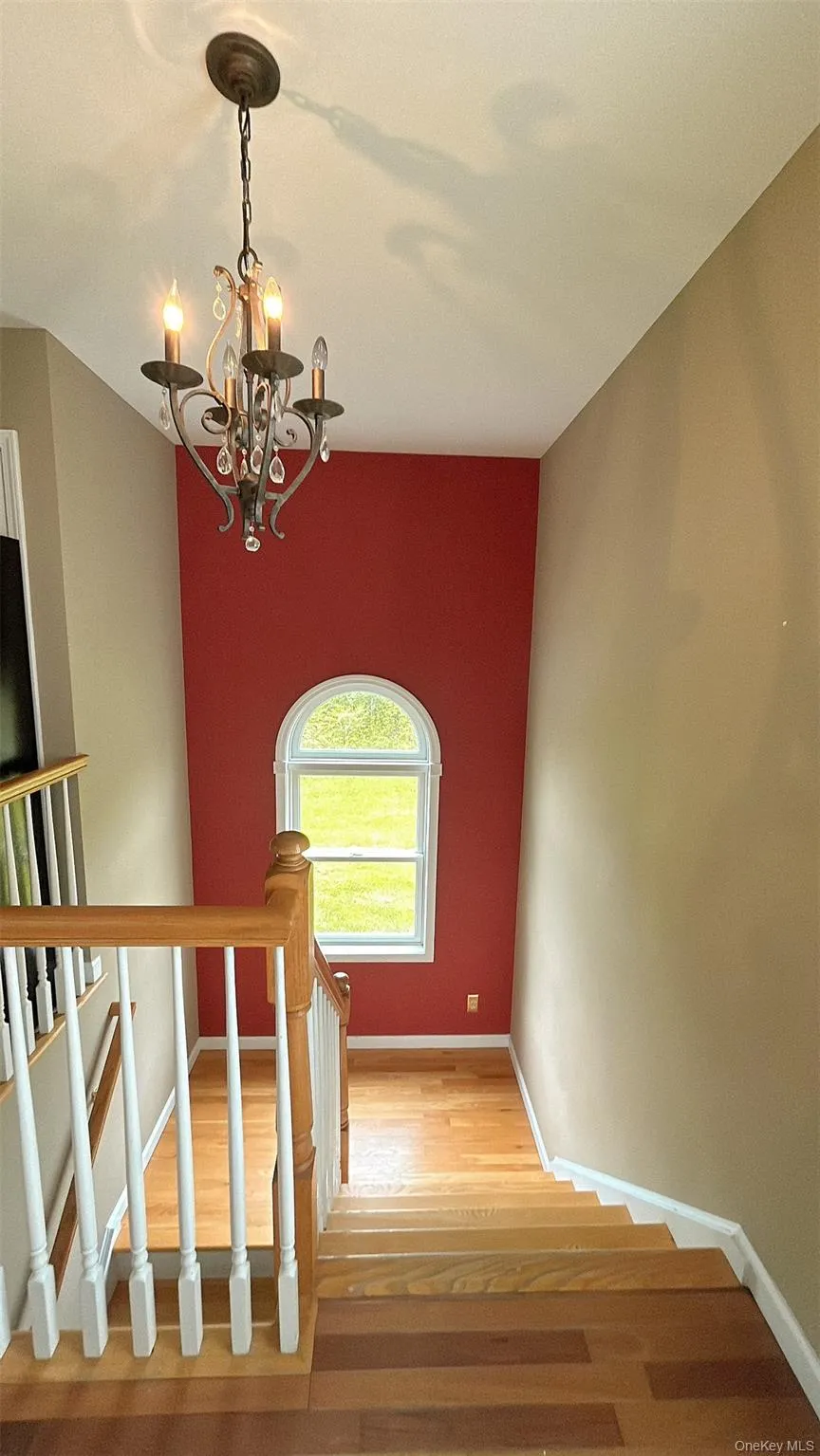 Stairway featuring wood finished floors and a chandelier Stairway featuring wood finished floors and a chandelier