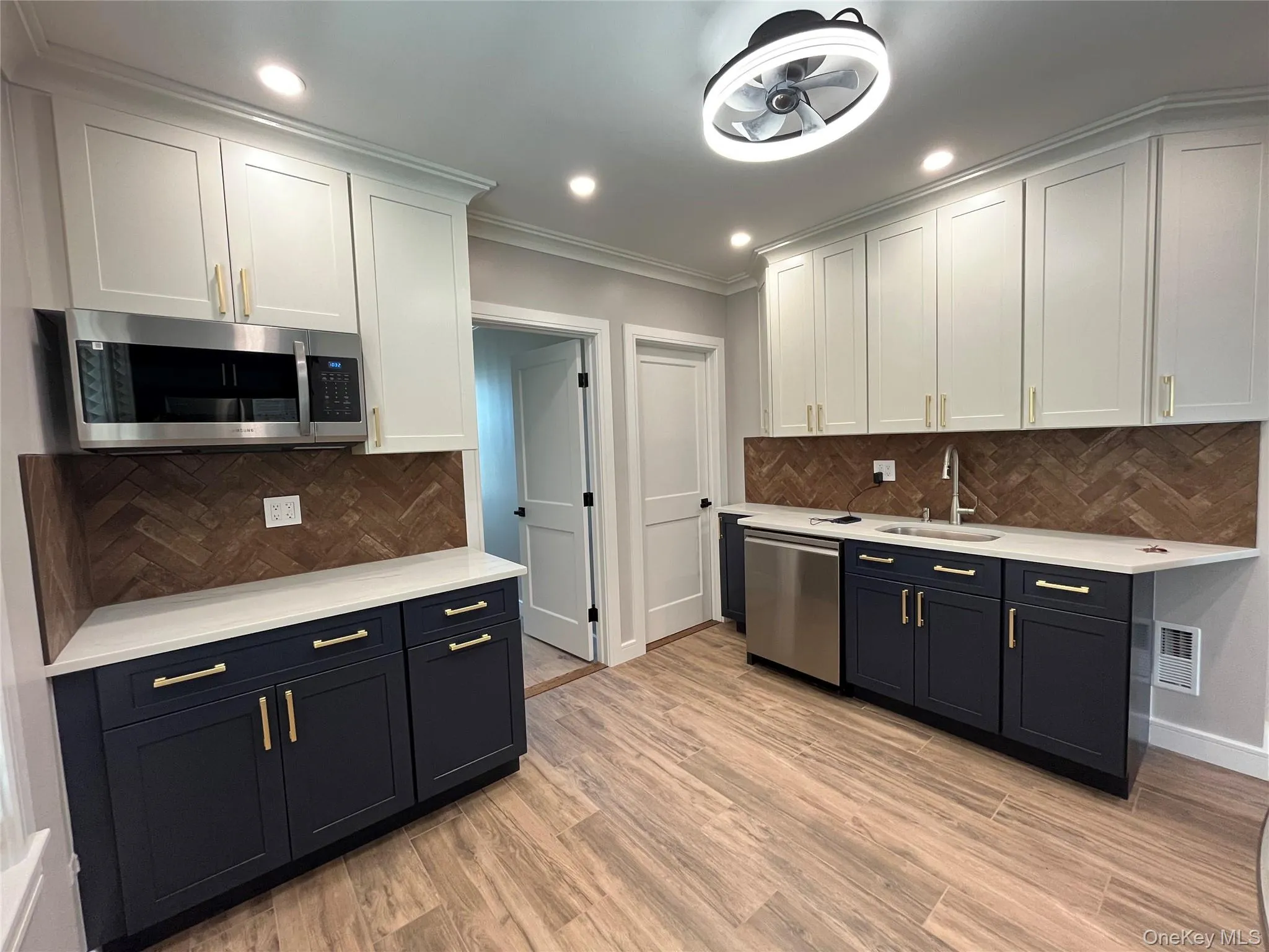 Kitchen with white cabinetry, stainless steel appliances, recessed lighting, light wood-type flooring, and light stone countertops Kitchen with white cabinetry, stainless steel appliances, recessed lighting, light wood-type flooring, and light stone countertops