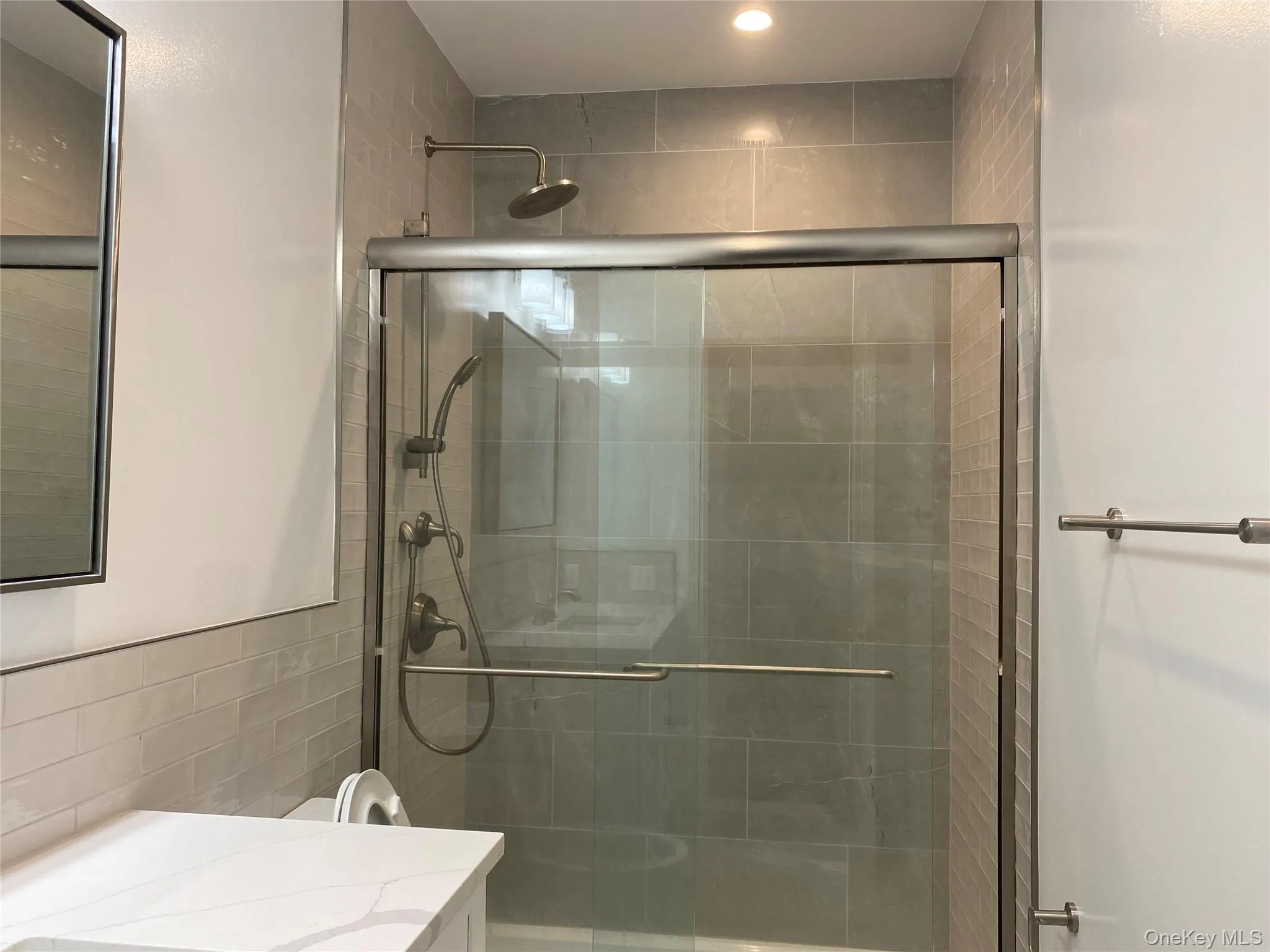 Bathroom with vanity, a shower stall, tile walls, and recessed lighting Bathroom with vanity, a shower stall, tile walls, and recessed lighting