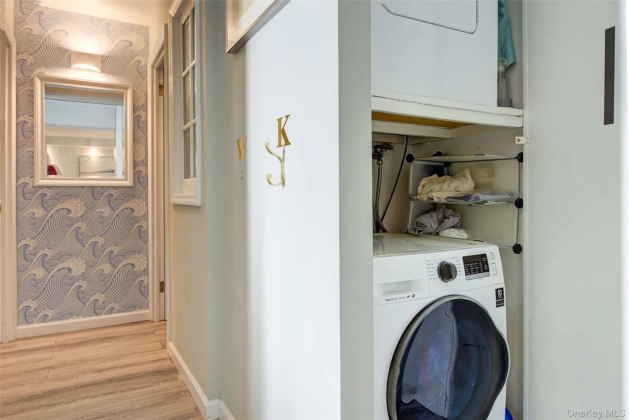 Laundry area with wallpapered walls and light wood-style floors Laundry area with wallpapered walls and light wood-style floors