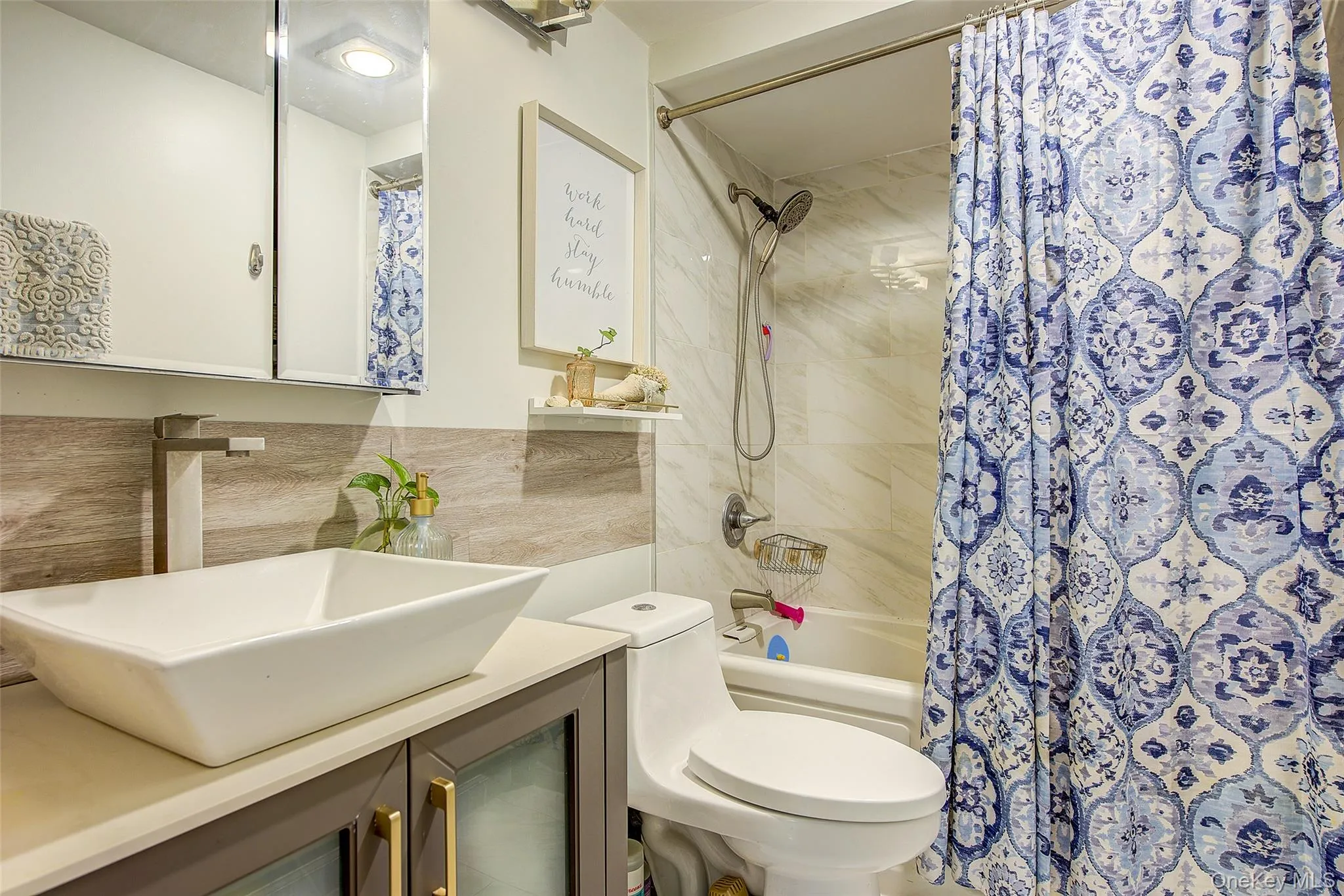 Full bathroom with shower / bath combination with curtain, vanity, and tile walls Full bathroom with shower / bath combination with curtain, vanity, and tile walls