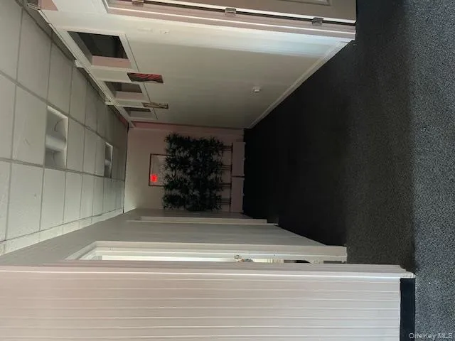 Hallway with a paneled ceiling and dark carpet Hallway with a paneled ceiling and dark carpet