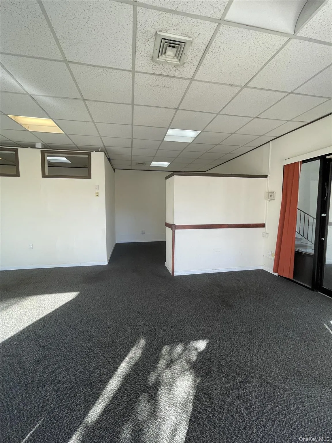 Unfurnished room featuring dark colored carpet and a paneled ceiling Unfurnished room featuring dark colored carpet and a paneled ceiling