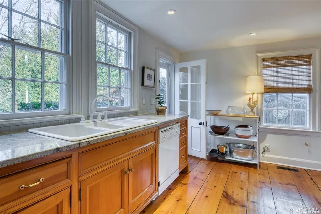 Kitchen featuring brown cabinetry, light wood-type flooring, light stone counters, dishwasher, and recessed lighting Kitchen featuring brown cabinetry, light wood-type flooring, light stone counters, dishwasher, and recessed lighting