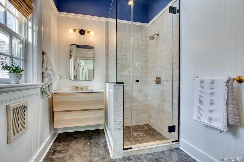 Full bathroom featuring a shower stall, vanity, and heating unit Full bathroom featuring a shower stall, vanity, and heating unit