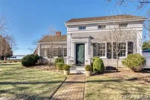 Greek revival house featuring a front yard and a chimney Greek revival house featuring a front yard and a chimney
