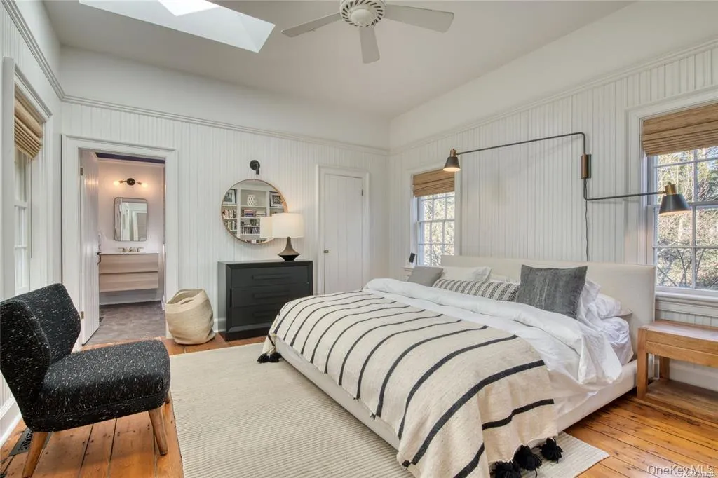 Bedroom with wood-type flooring, ceiling fan, and a skylight Bedroom with wood-type flooring, ceiling fan, and a skylight