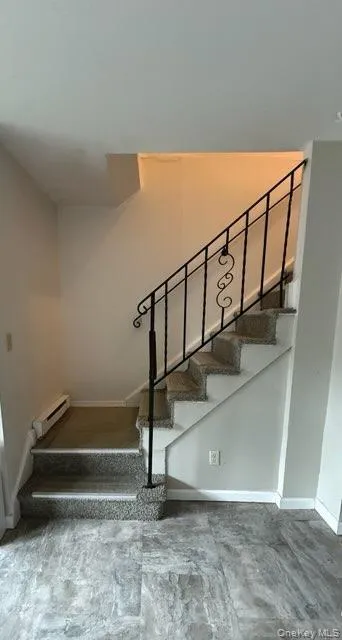 Staircase featuring a baseboard radiator and baseboards Staircase featuring a baseboard radiator and baseboards