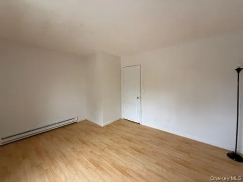 Empty room featuring light wood finished floors and baseboard heating Empty room featuring light wood finished floors and baseboard heating