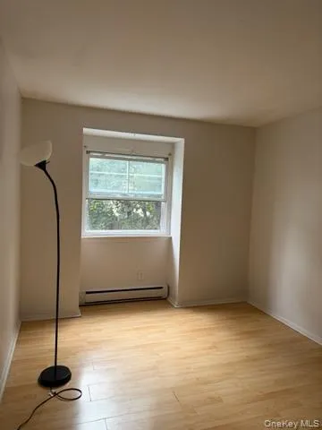Empty room featuring light wood-type flooring and a baseboard radiator Empty room featuring light wood-type flooring and a baseboard radiator