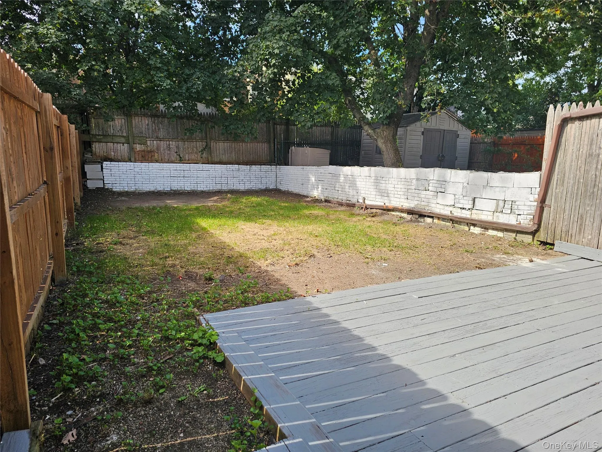 Fenced backyard featuring a storage unit and a deck Fenced backyard featuring a storage unit and a deck