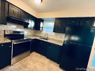 Kitchen with black appliances, tasteful backsplash, and under cabinet range hood Kitchen with black appliances, tasteful backsplash, and under cabinet range hood
