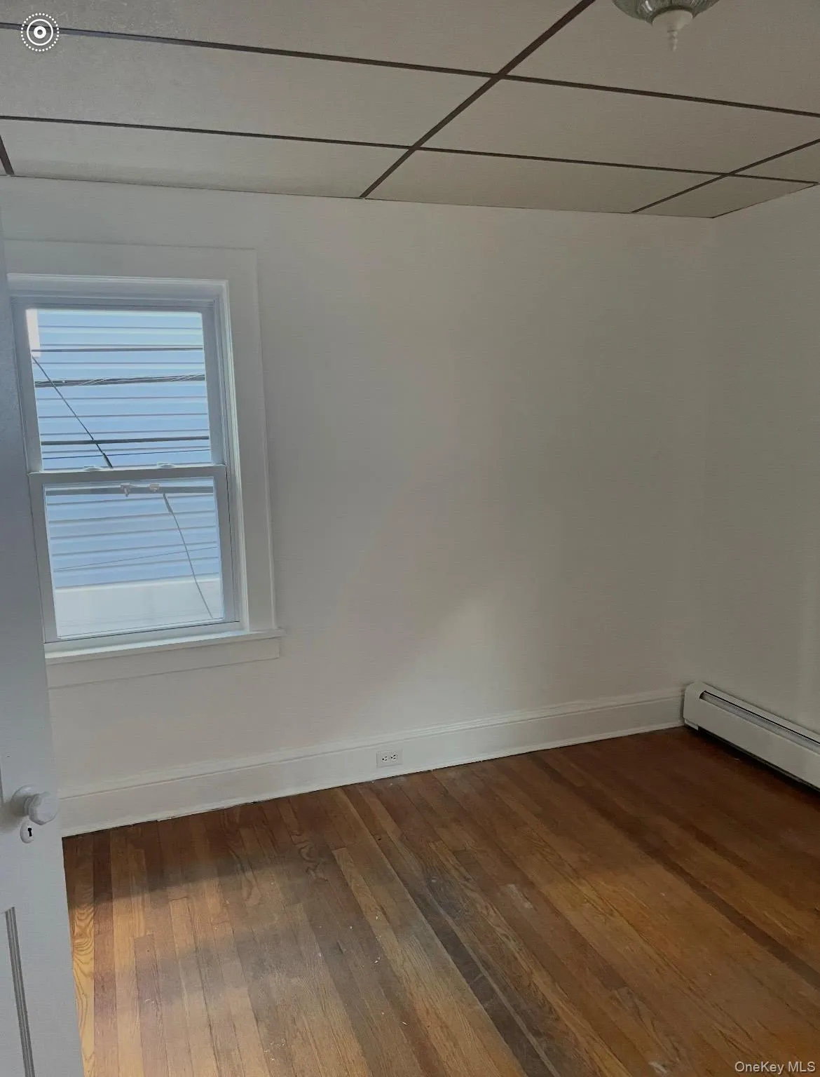 Spare room with a baseboard heating unit, cooling unit, and dark wood finished floors Spare room with a baseboard heating unit, cooling unit, and dark wood finished floors