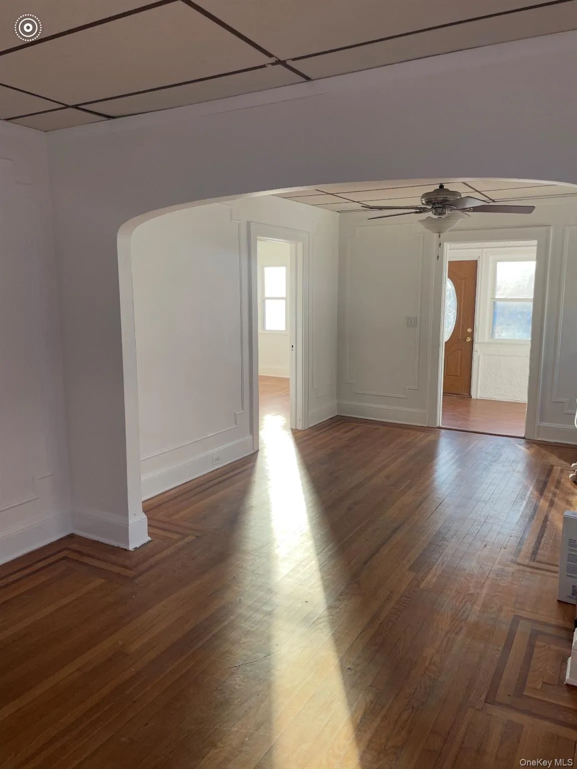 Spare room featuring arched walkways, dark wood-style floors, a ceiling fan, and a paneled ceiling Spare room featuring arched walkways, dark wood-style floors, a ceiling fan, and a paneled ceiling
