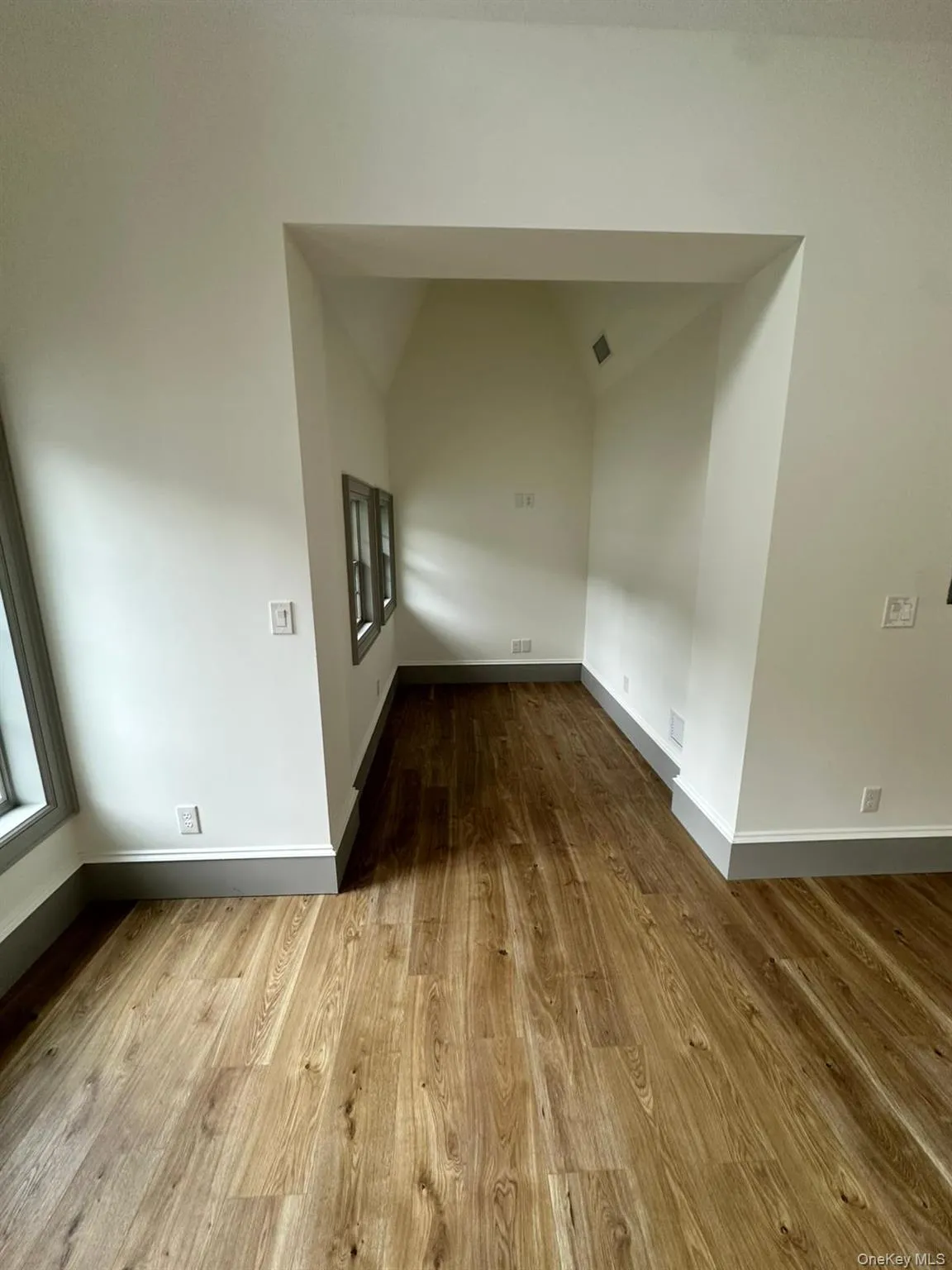 Spare room with wood finished floors and lofted ceiling Spare room with wood finished floors and lofted ceiling