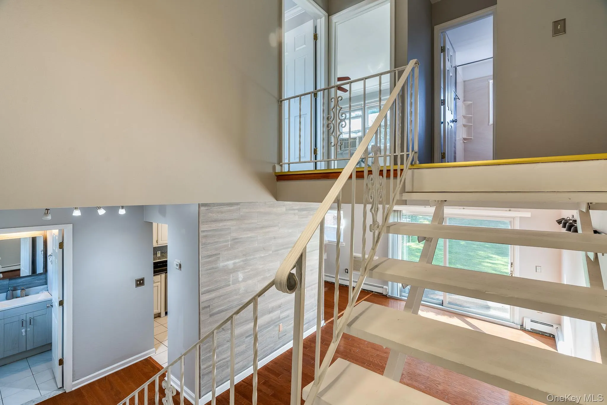 Staircase with plenty of natural light, wood finished floors, and baseboard heating Staircase with plenty of natural light, wood finished floors, and baseboard heating