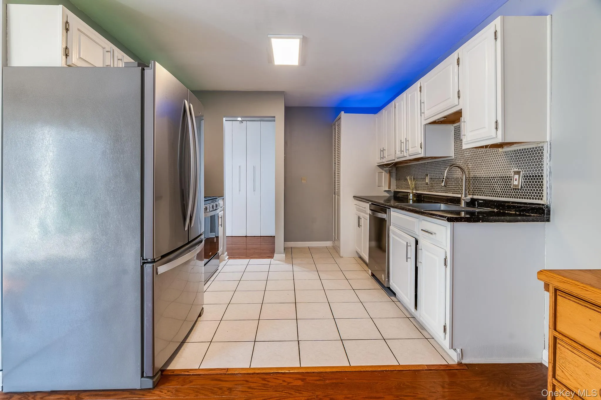 Kitchen with appliances with stainless steel finishes, dark stone countertops, white cabinetry, and decorative backsplash Kitchen with appliances with stainless steel finishes, dark stone countertops, white cabinetry, and decorative backsplash