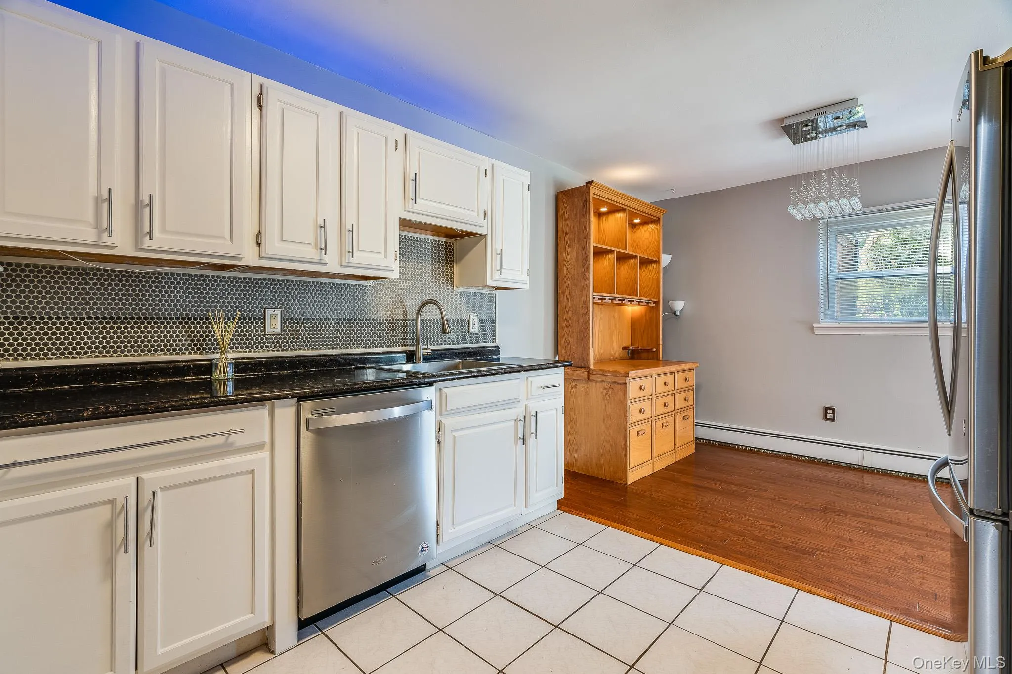 Kitchen with tasteful backsplash, light tile patterned floors, white cabinetry, and stainless steel appliances Kitchen with tasteful backsplash, light tile patterned floors, white cabinetry, and stainless steel appliances