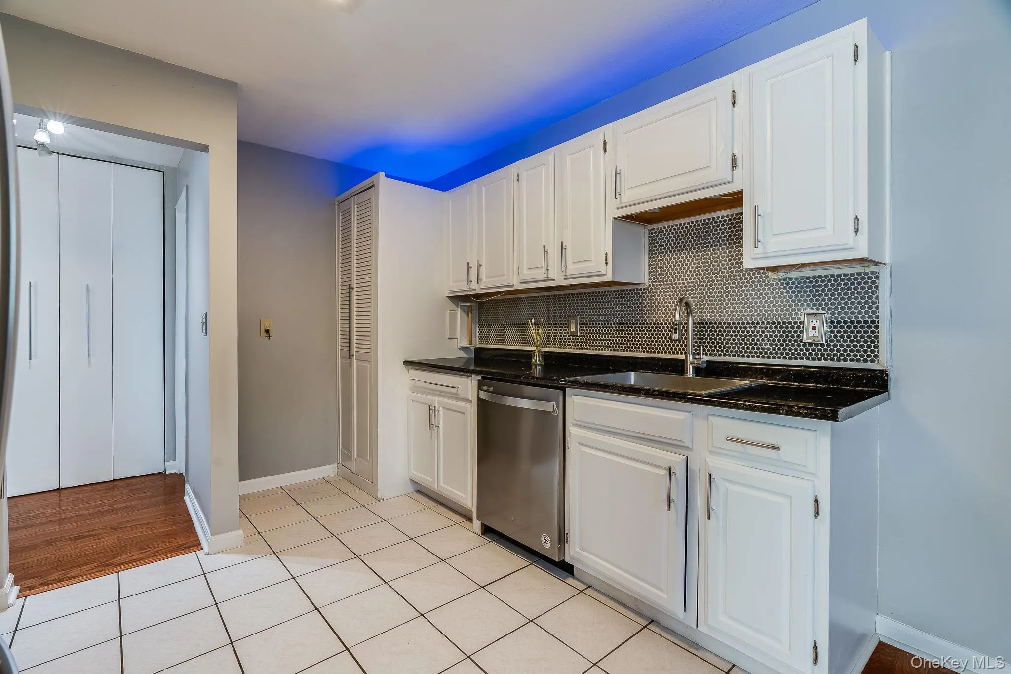 Kitchen featuring white cabinetry, light tile patterned floors, dark stone counters, and backsplash Kitchen featuring white cabinetry, light tile patterned floors, dark stone counters, and backsplash
