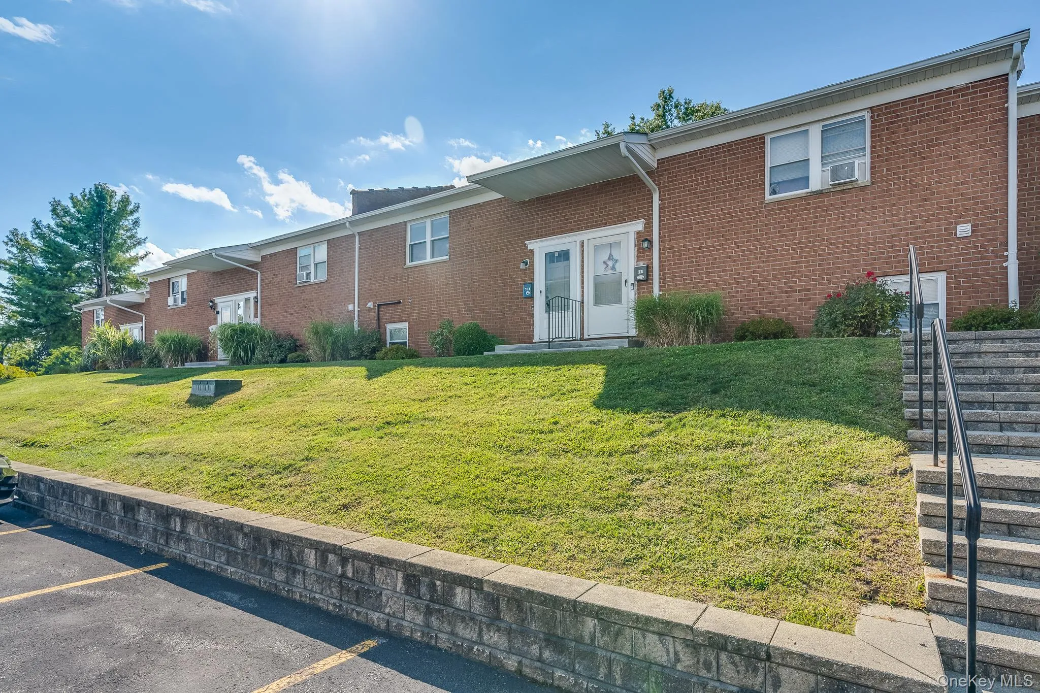 View of front of property with brick siding, a front yard, and uncovered parking View of front of property with brick siding, a front yard, and uncovered parking