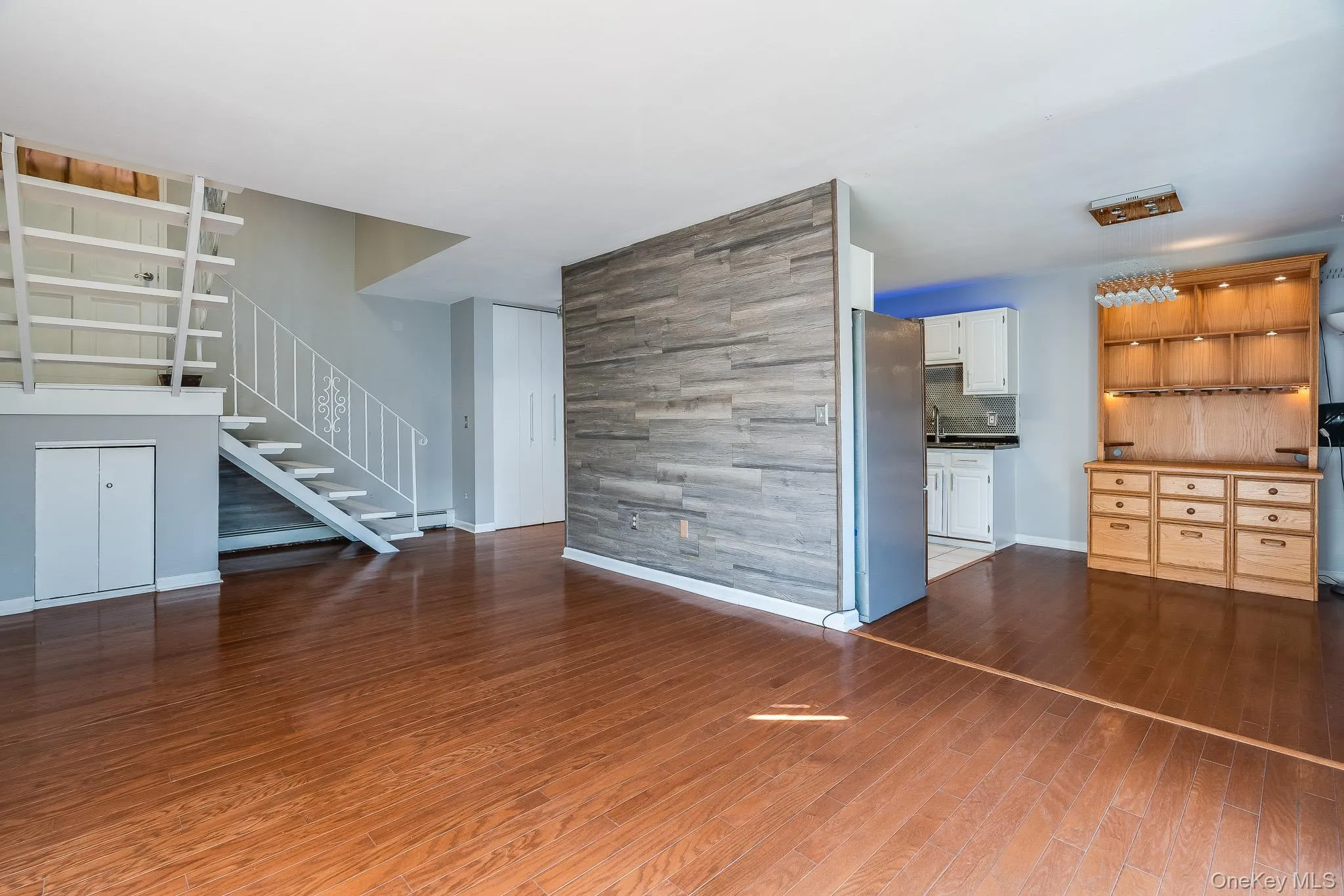 Unfurnished living room with dark wood-style floors and stairway Unfurnished living room with dark wood-style floors and stairway