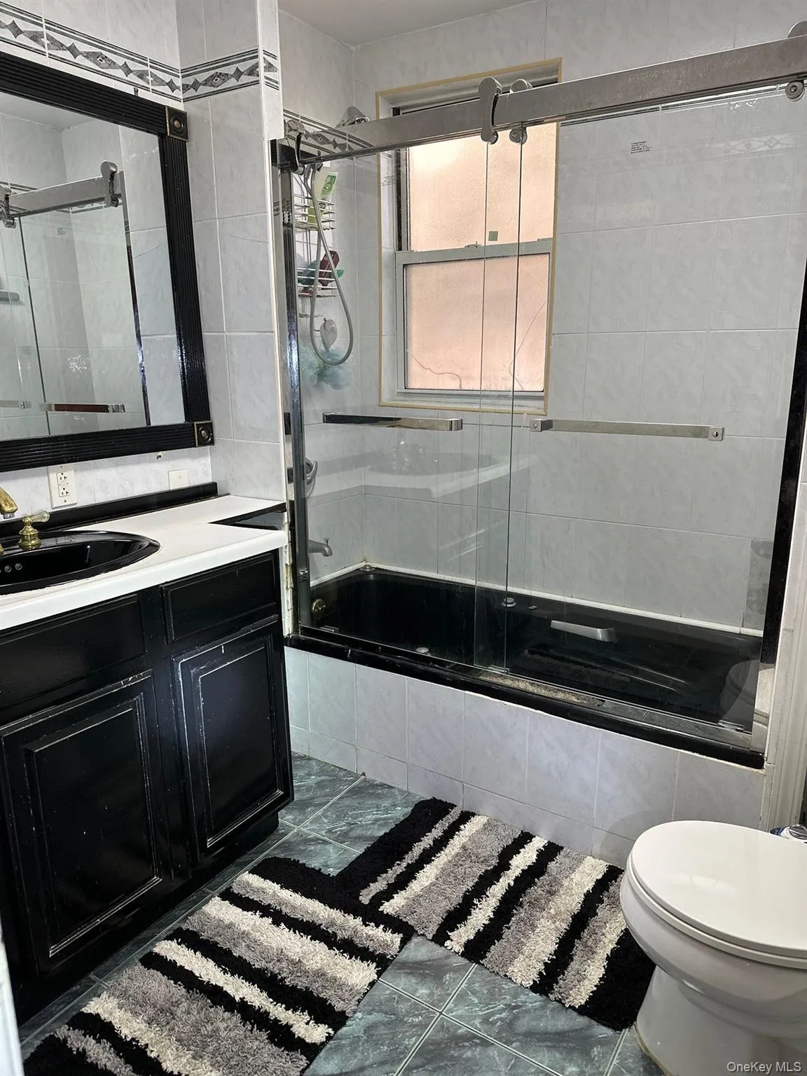 Bathroom with tiled shower / bath combo, vanity, and dark tile patterned floors Bathroom with tiled shower / bath combo, vanity, and dark tile patterned floors