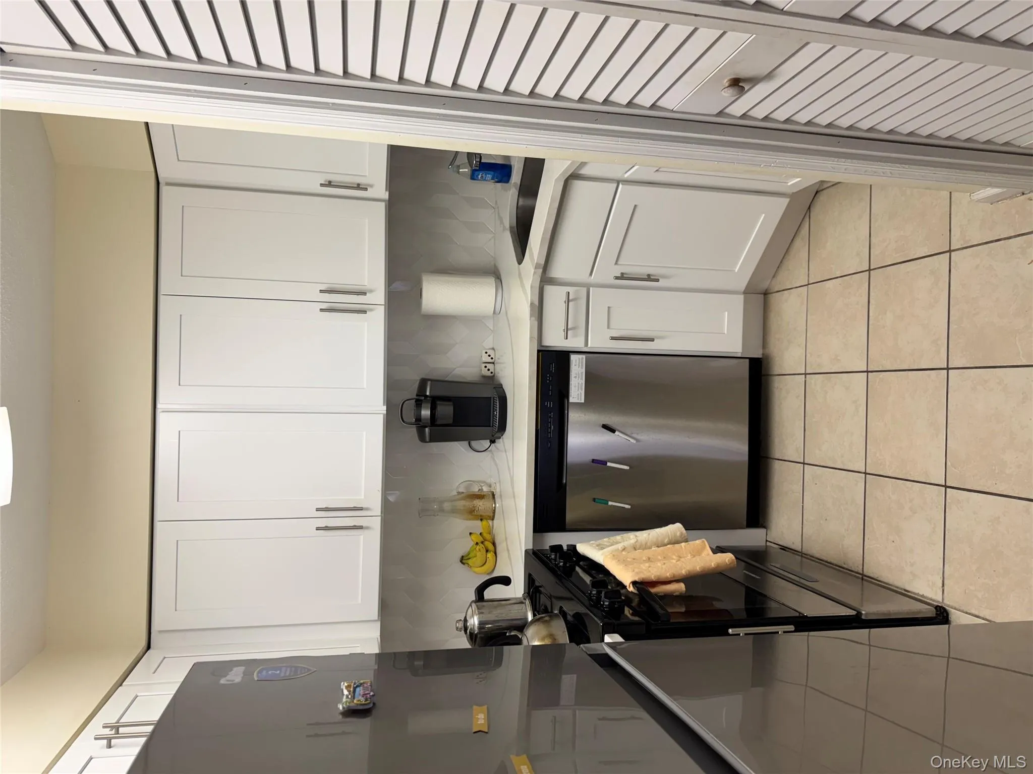 Kitchen with white cabinetry, dishwasher, light tile patterned floors, stove, and tasteful backsplash Kitchen with white cabinetry, dishwasher, light tile patterned floors, stove, and tasteful backsplash
