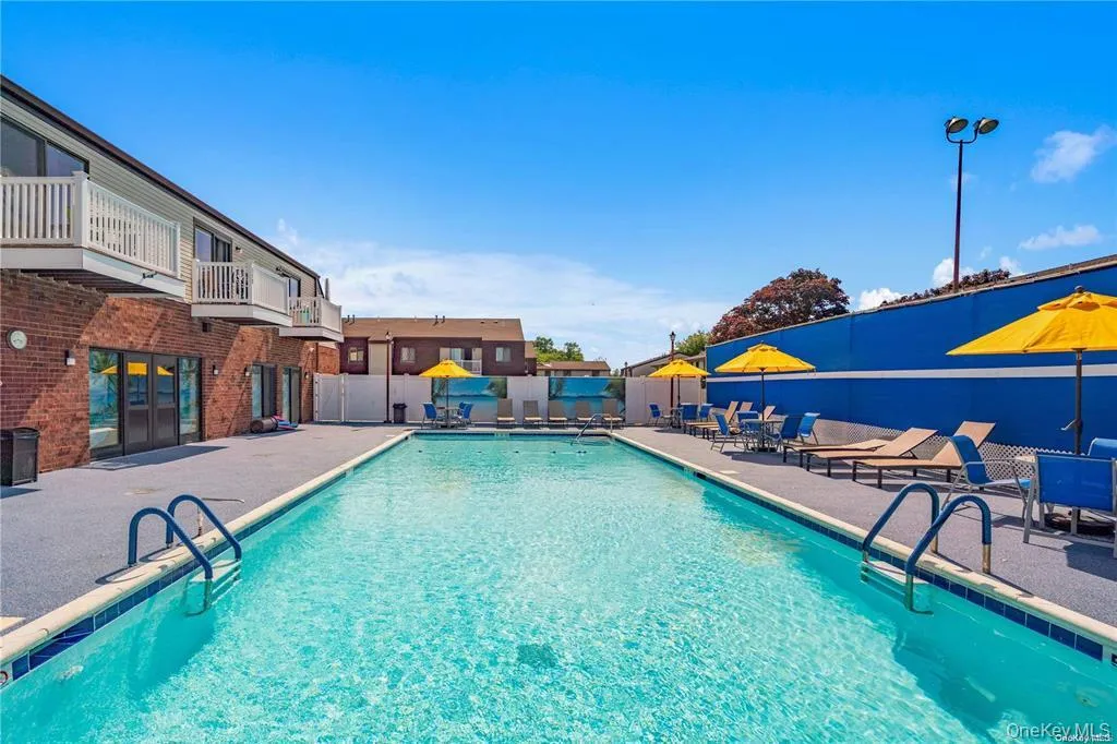 Community pool with a patio area, a balcony, and a residential view Community pool with a patio area, a balcony, and a residential view
