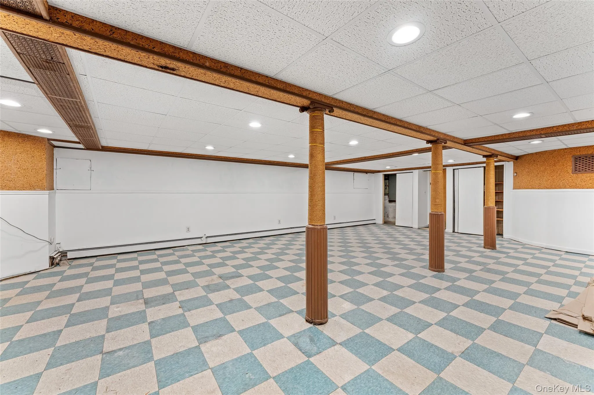 Finished basement with wainscoting, recessed lighting, light floors, and baseboard heating Finished basement with wainscoting, recessed lighting, light floors, and baseboard heating