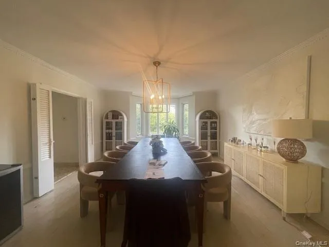 Dining room featuring crown molding, wood finished floors, and a chandelier Dining room featuring crown molding, wood finished floors, and a chandelier