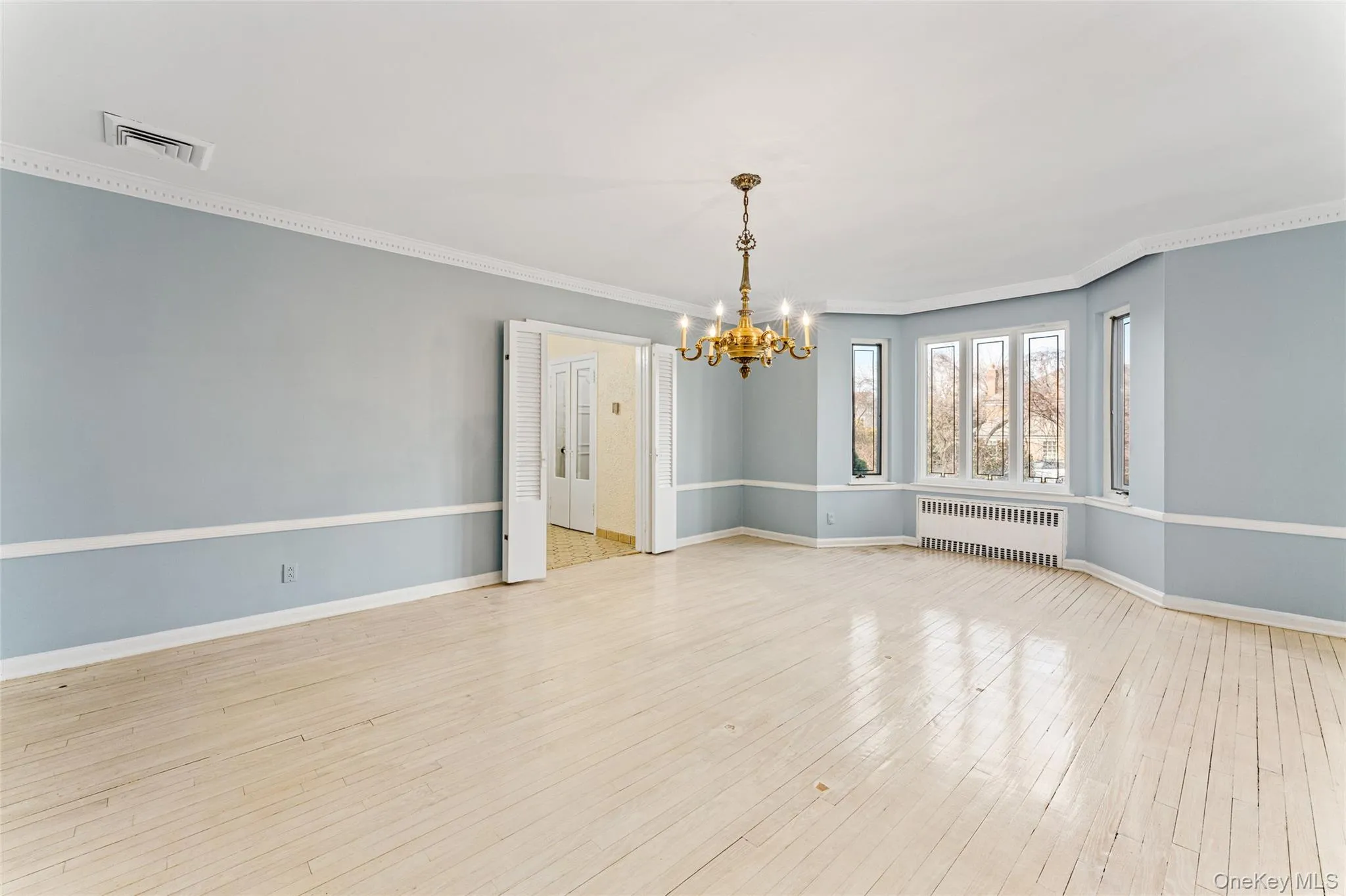 Unfurnished dining area featuring a chandelier, crown molding, radiator, and light wood-style flooring Unfurnished dining area featuring a chandelier, crown molding, radiator, and light wood-style flooring