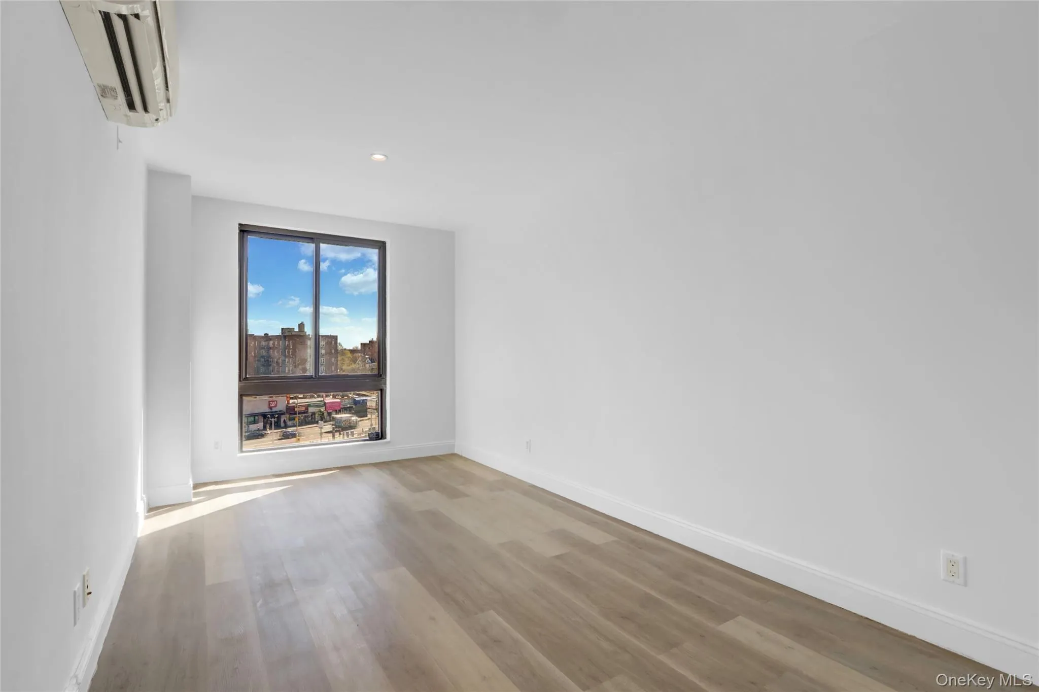 Spare room featuring a wall unit AC, light wood-style floors, recessed lighting, and a view of city Spare room featuring a wall unit AC, light wood-style floors, recessed lighting, and a view of city