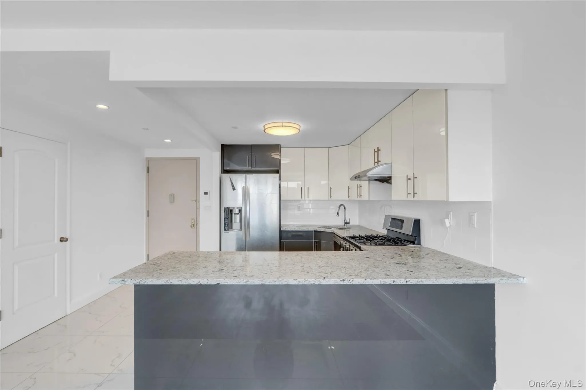 Kitchen featuring tasteful backsplash, stainless steel appliances, light stone counters, a peninsula, and recessed lighting Kitchen featuring tasteful backsplash, stainless steel appliances, light stone counters, a peninsula, and recessed lighting